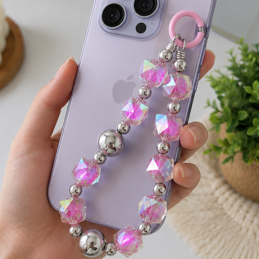 Smartphone with a pink and silver beaded lanyard held by a hand on a light background